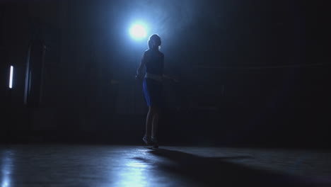 mujer boxeadora saltando con una cuerda en la sala de boxeo con un anillo