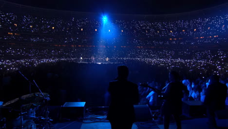 live concert in a stadium with a crowd holding lights