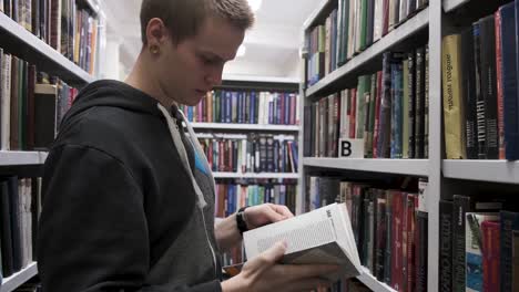 young man looking at books in a library