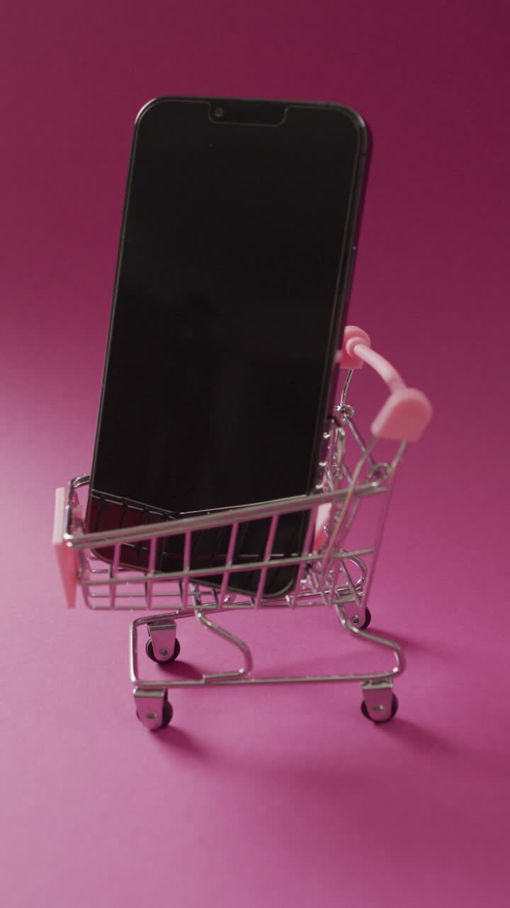 Video verticale di smartphone nel carrello della spesa su sfondo rosa.