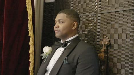 groom sitting as he is photographed on his wedding day