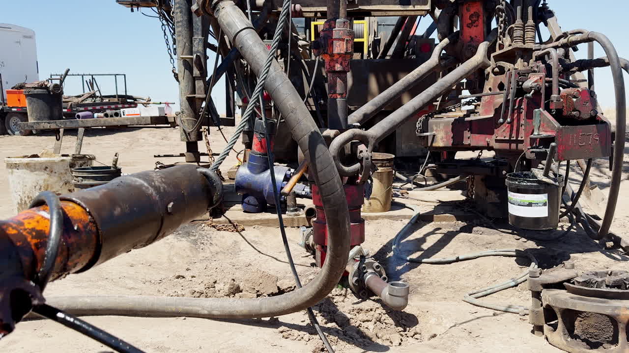Diverse equipment in the drilling location. Blue gas goes up from a curved pipe. Technological process of gas extraction.