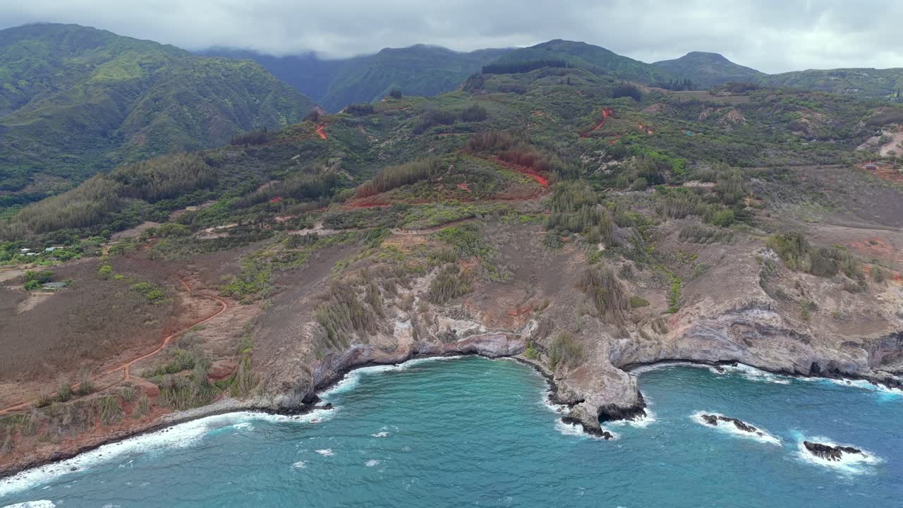 Drone pans across a rocky Hawaiian shore rarely seen by visitors, revealing epic cliff faces and turning to show the magnificent view of the island from the sea. 5 of sequence of 5