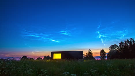 cabaña durante la puesta de sol y la hora azul desde un prado rural con flores