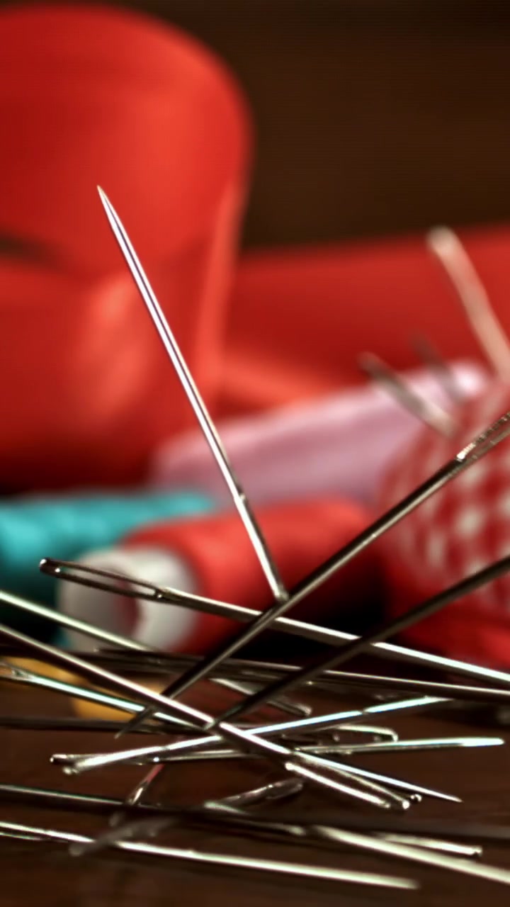 Sewing Needles Falling in Slow Motion onto a Wooden Table