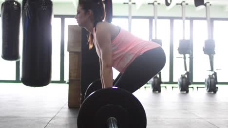 footage of a pregnant female model doing squats in a gym trying to keep fit in her fourth trimester