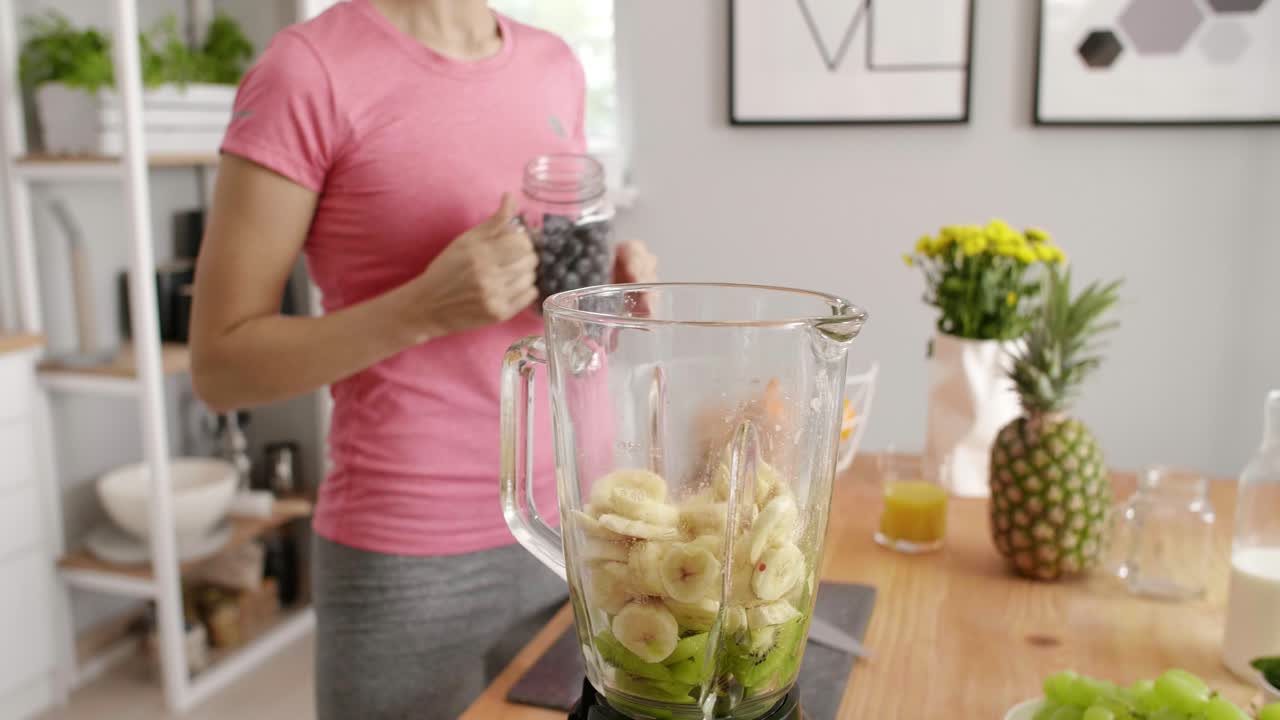 parte de una mujer preparando un batido de frutas en la cocina