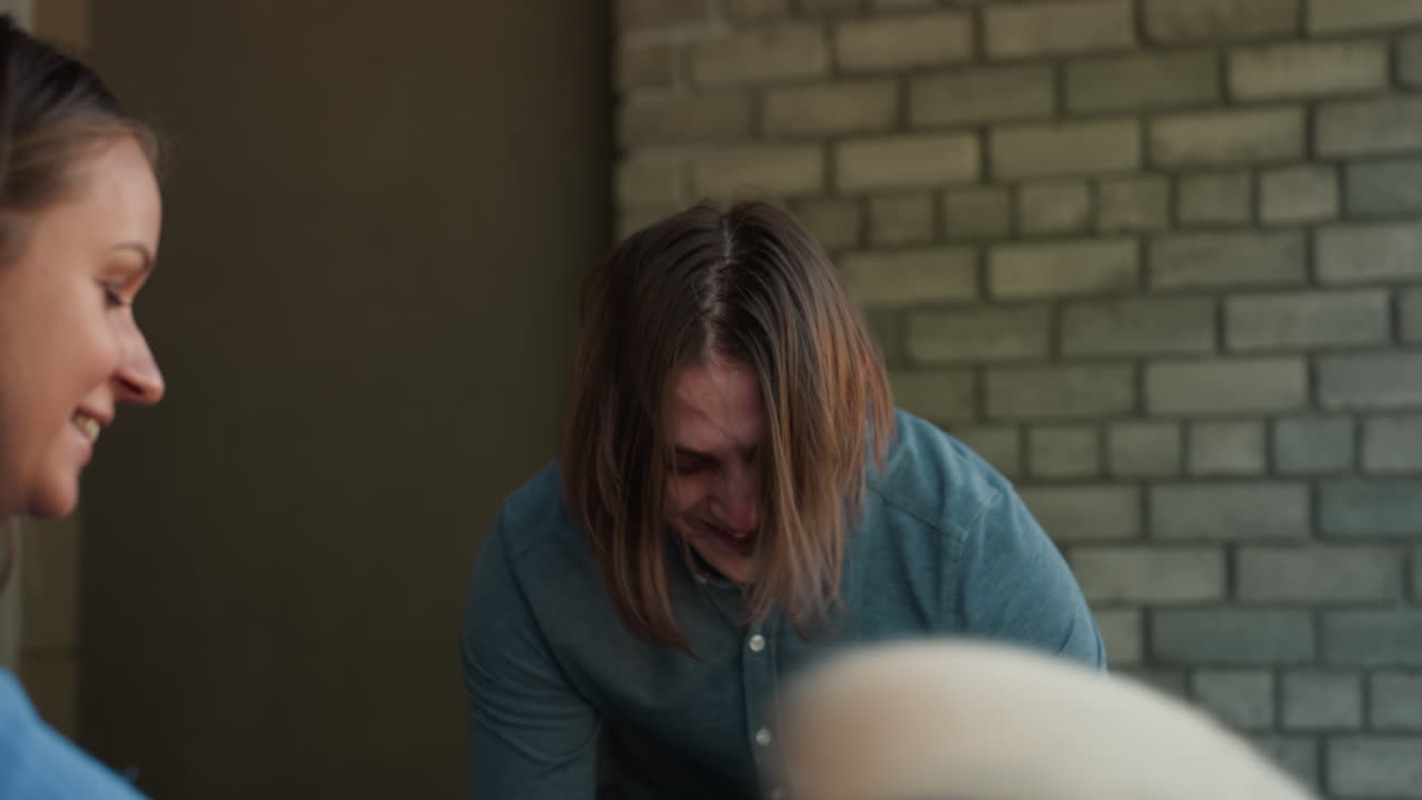 Hombre caucásico acariciando un labrador en un refugio cerca de una ventana y una pared de ladrillo, voluntario saludando al perro con un toque suave y una cálida sonrisa, escena de adopción en interior que muestra un vínculo de calma y unas manos atentas