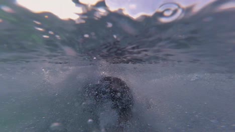 hombre se sumerge con tabla de surf bajo el agua para pasar la ola del océano