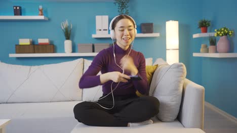 asian woman dancing and listening to music on her phone with headphones.