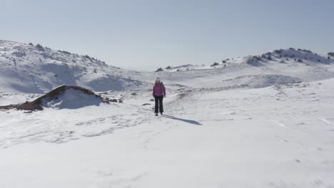 4k-Drohnenüberführung-Schöne-Junge-Frau,-Die-Allein-In-Schneebedeckten-Bergen-Klettert