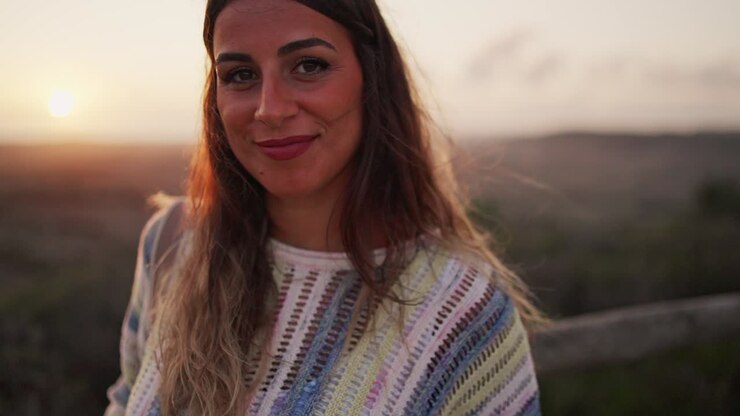 Joven modelo morena mirando seductoramente y sonriendo a la cámara en un mirador al atardecer.