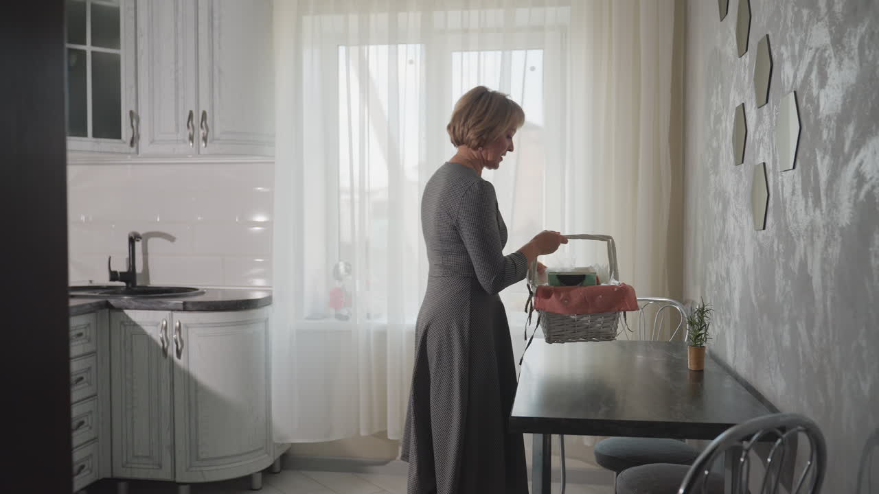 Back view of business woman entering bright kitchen dropping shopping basket on table unpacking items placing purchases on dark surface cozy home interior