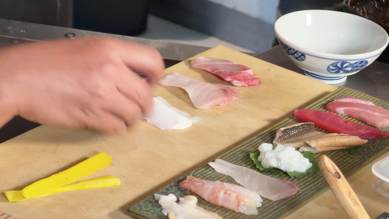 Close-up of chef arranging assorted sashimi slices on board beside plated seafood assortment