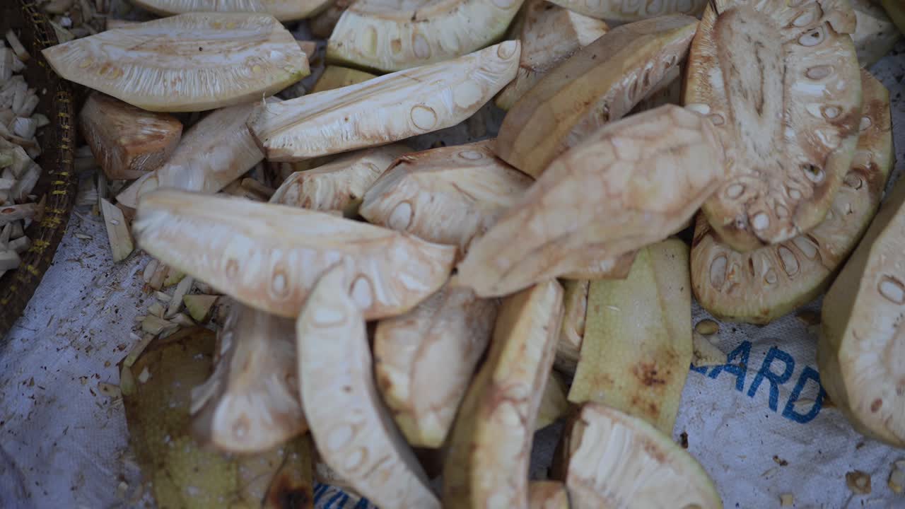 Primo piano del processo di persone che preparano cibo da pezzi di giovane jackfruit in un mercato tradizionale.