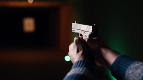 man holding pistol at indoor shooting range, close up