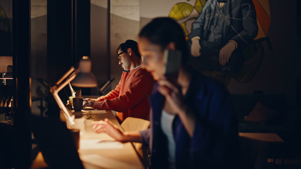 Two consultants talking mobile phones at night workspace. Confident woman