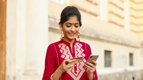 portrait of an indian woman with a credit card and a smartphone in her hands