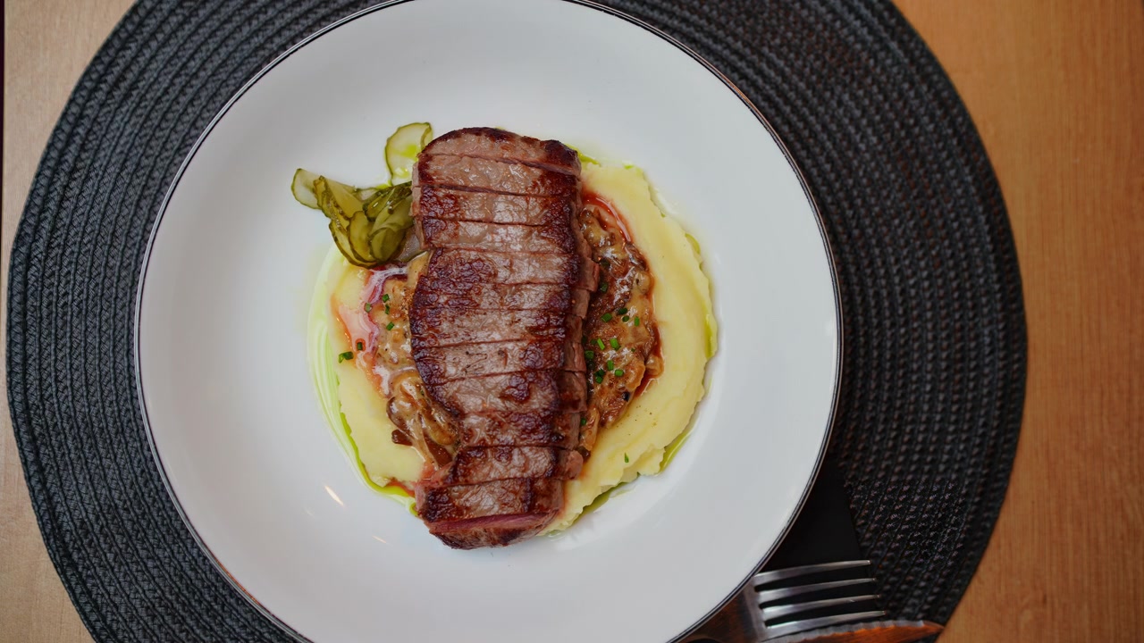 Sirviendo filete de ternera en rodajas sobre puré de patatas