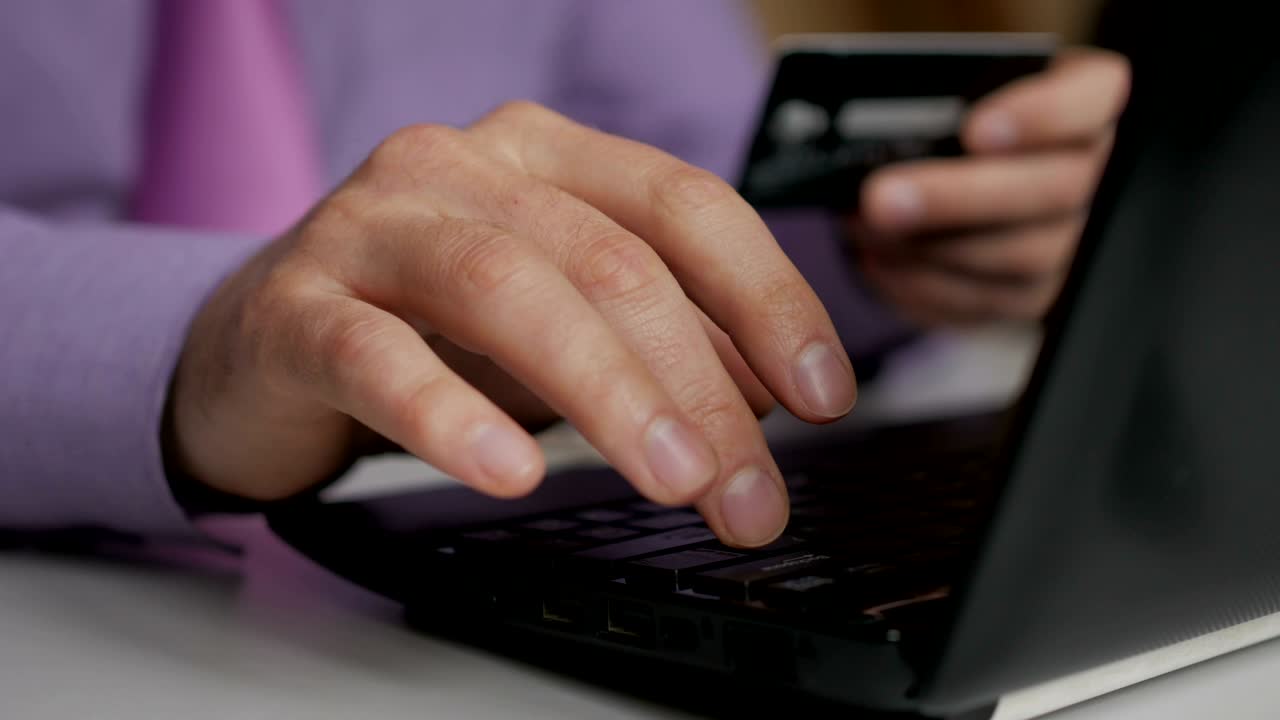 un hombre de negocios con una camisa púrpura y corbata está haciendo un pago a la banca por internet. compras en línea con tarjeta de crédito en la computadora portátil.
