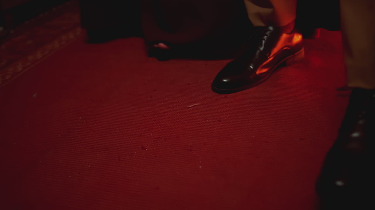 hombre poniéndose zapatos en una alfombra roja