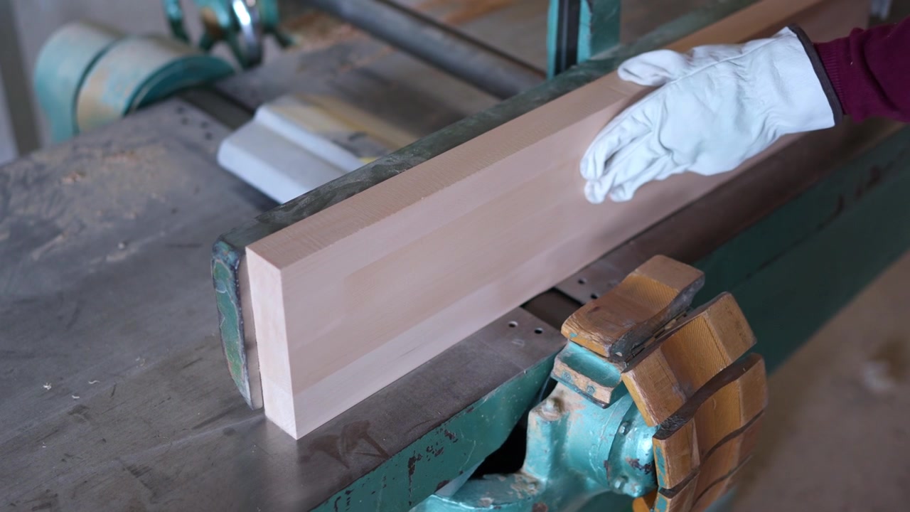 Falegname che pialla un'asse di legno con la piallatrice