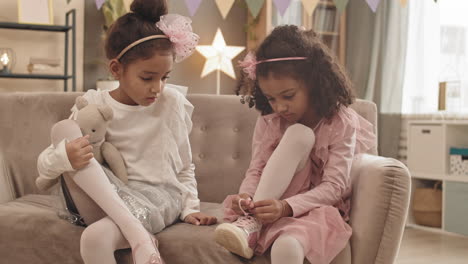 sister watching girl lacing shoe
