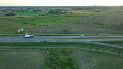 wide aerial view of a highway intersection poland, surrounded by open farmland and green fields, with vehicles traveling along the road at sunset