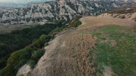 fast fpv cruising drone shot over the hilly landscape of calanchi di aliano in italy during sunset