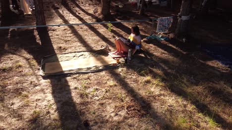 orbit shot of young woman reading book in camp in wild pine forest