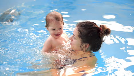 baby in the pool jumping from the side into the water and swims to his mother in slow motion