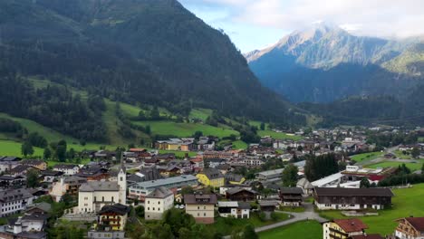 aerial view of austrian village surrounded by mountains during summer, lush green hills and blue sky - landscape panorama of alps from above, austria, europe