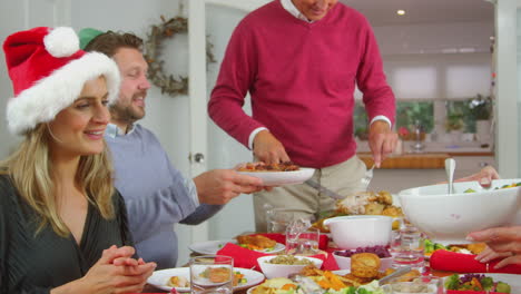 Mehrgenerationenfamilie-Mit-Weihnachtsmützen-Genießt-Das-Gemeinsame-Weihnachtsessen-Zu-Hause