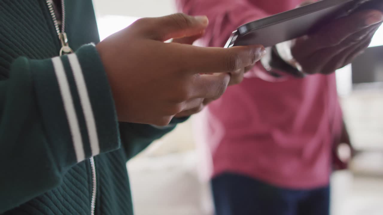 Video of hands of nervous african american father taking his son smartphone and arguing in kitchen
