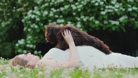 young pregnant woman relaxes on a lawn plays with a pet