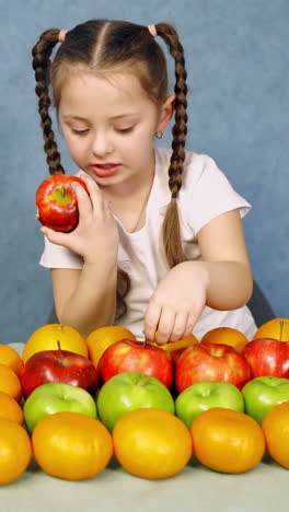 little girl with fruits on table. portrait of beautiful little girl sitting with apples at table