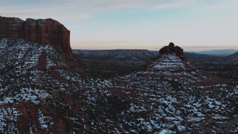 Formaciones-Rocosas-Rojas-Bajo-La-Nieve-En-Sedona,-Arizona-Al-Atardecer---Disparo-Aéreo-De-Drones