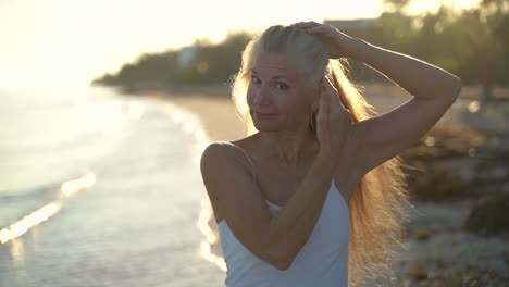 Closeup-slow-motion-of-backlit-mature-woman-showing-us-her-gray-hair-and-laughing,-celebrating-her-age