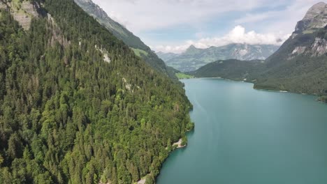 Aerial-view-of-Klöntalersee-lake-in-the-Klöntal-valley,-with-Vorderglärnisch-mountain-and-lush-forests-in-Switzerland