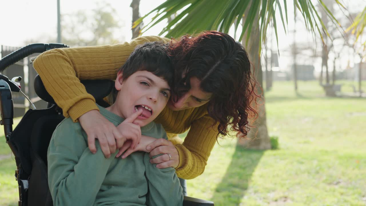 Loving mother caring for her disabled son in a wheelchair at the park