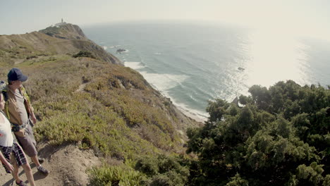 Father-and-daughter-hiking-at-mountain-top,-standing-on-cliff-and-enjoying-view-of-sea