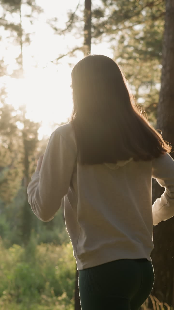 la mujer corredora disfruta del entrenamiento en el bosque al atardecer. la mujer activa hace una carrera nocturna pasando por los árboles bajo la cálida luz del sol. ejercicios de fitness para mejorar la forma del cuerpo