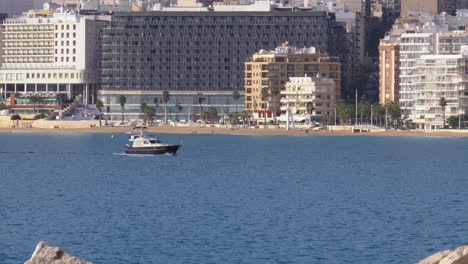 Motoryacht-Auf-Blauem-Meer-Mit-Blick-Auf-Strandhotels,-Calpe,-Spanien