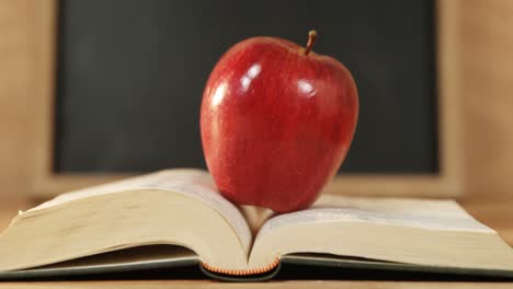 un primer plano de una manzana roja con un libro abierto