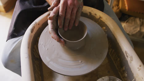 Close-up-view-of-male-potter-creating-pottery-on-on-potters-wheel-at-pottery-studio