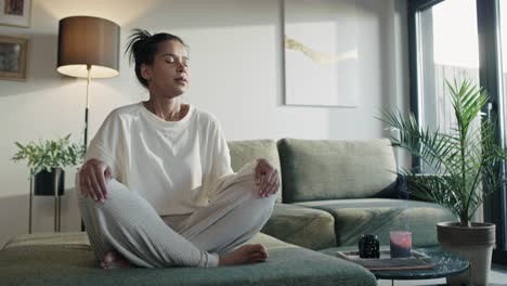 mujer natural meditando en casa con los ojos cerrados.