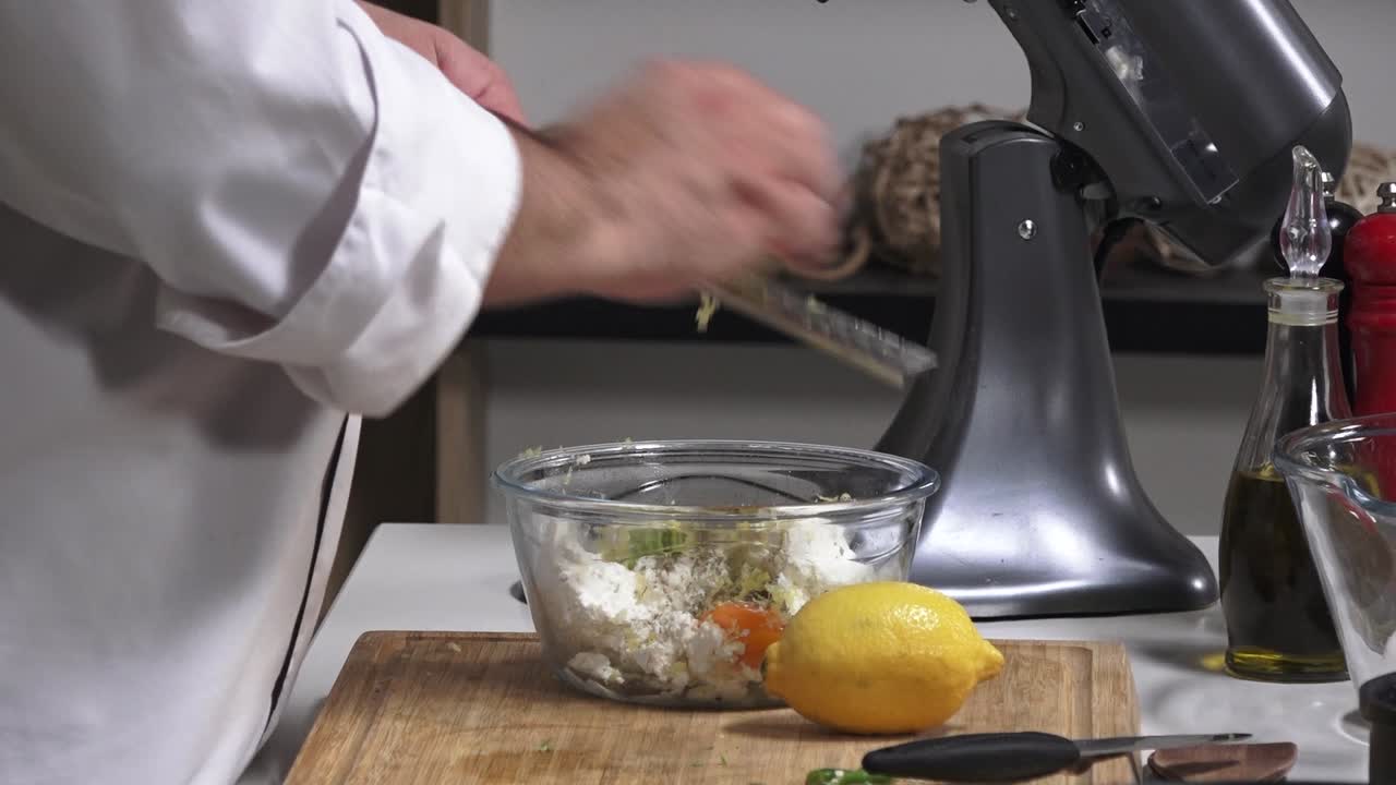 A chef prepares delicious dishes using fresh vegetables, cheese, and lemons in a clean, contemporary kitchen. The mixer adds convenience to the cooking process