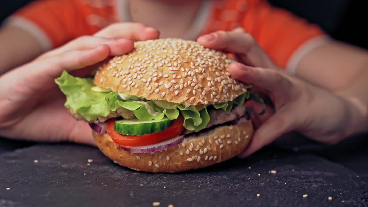 Young teenager eating tasty hamburger in fast food restaurant