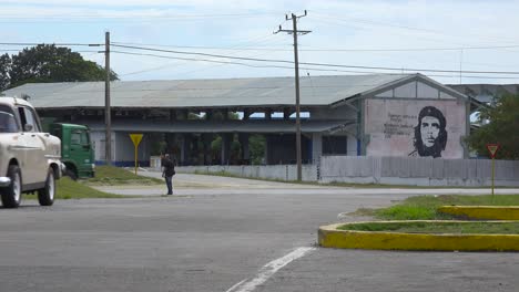 A-car-drives-down-a-road-near-a-building-decorated-with-Che-revolutionary-painting-in-Communist-Cuba-1