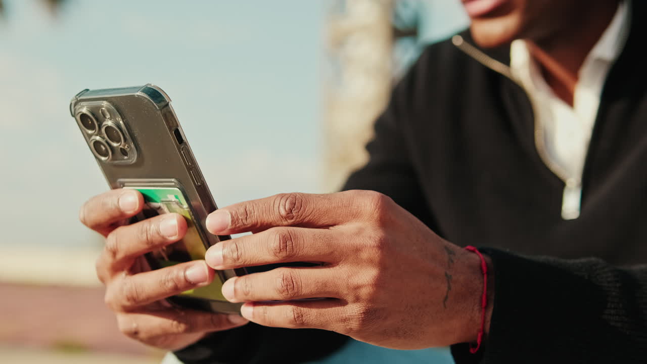 Close-Up of Man's Hands Holding and Using Smartphone Outdoors